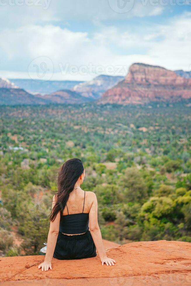 Young hiker woman on the edge of a cliff at Cathedral Rock in Sedona, Arizona. View from Scenic Cathedral Rock in Sedona with blue sky in Arizona photo