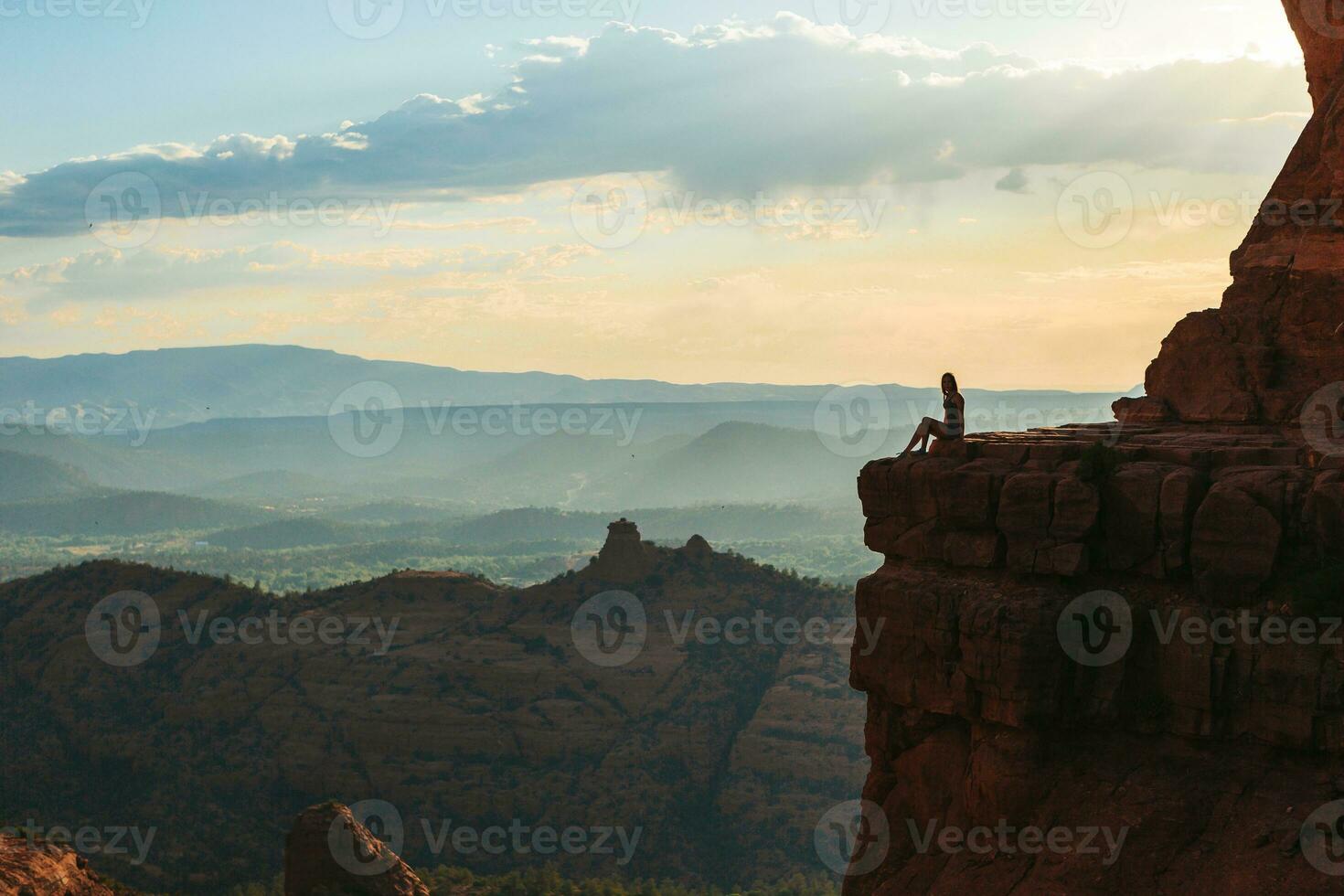 Young hiker woman on the edge of a cliff at Cathedral Rock in Sedona, Arizona. View from Scenic Cathedral Rock in Sedona with blue sky in Arizona photo