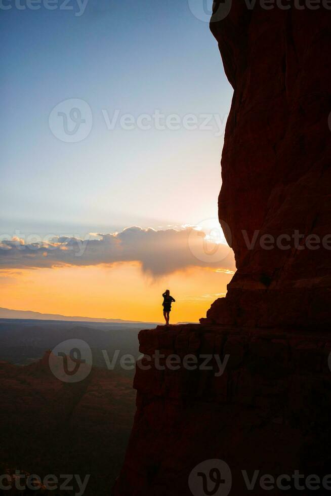 Young hiker woman on the edge of a cliff at Cathedral Rock in Sedona, Arizona. View from Scenic Cathedral Rock in Sedona with blue sky in Arizona photo