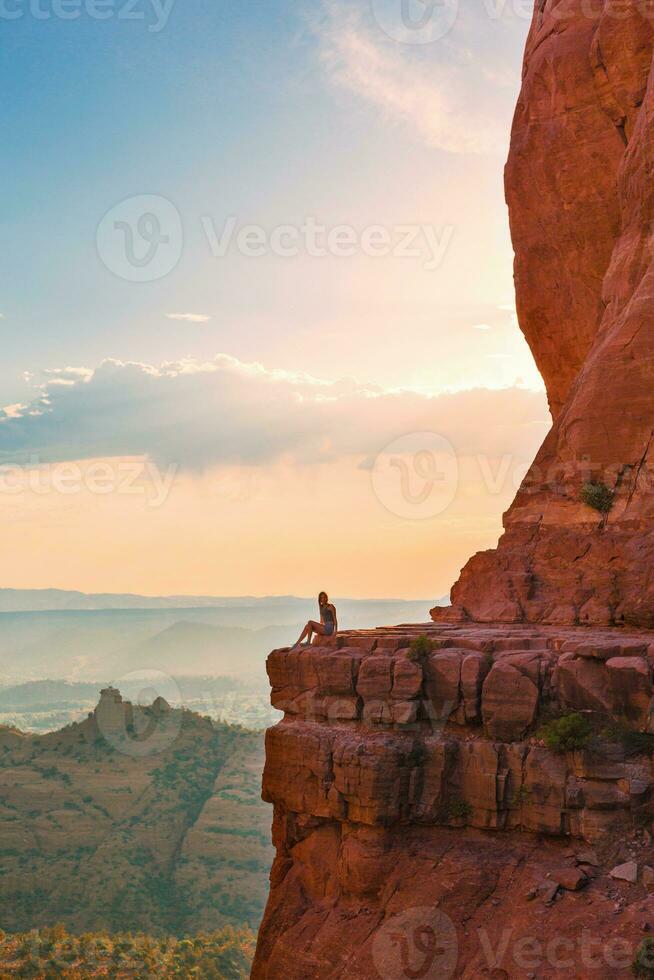 Little girl on the edge of a cliff at Cathedral Rock in Sedona, Arizona. View from Scenic Cathedral Rock in Sedona with blue sky in Arizona photo