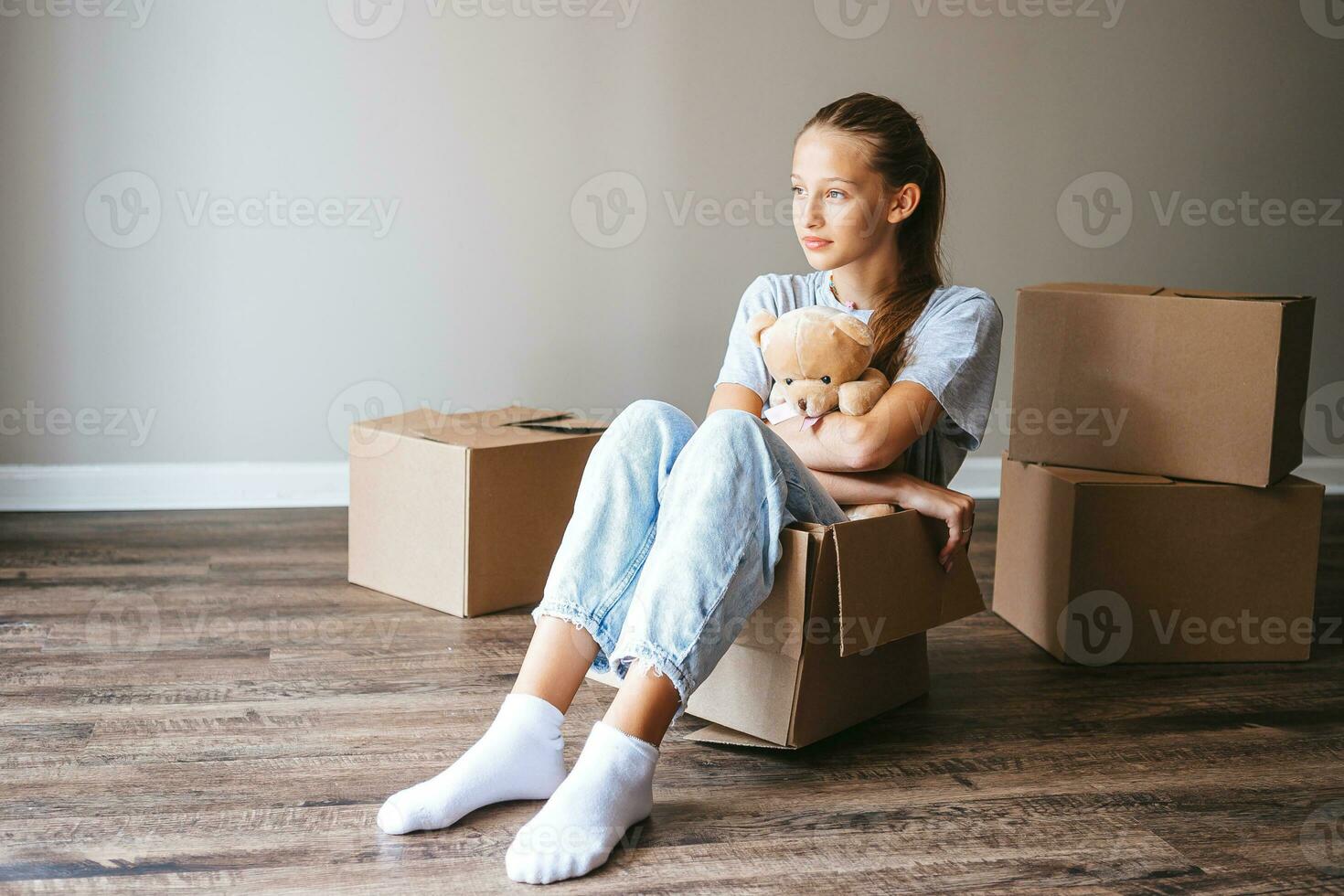 Happy adorable girl with cardboard boxes in new house at moving day photo