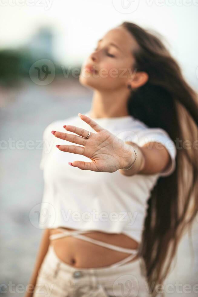Adorable young girl with beautiful long hair enjoy tropical beach vacation. The girl on the seashore at sunset photo