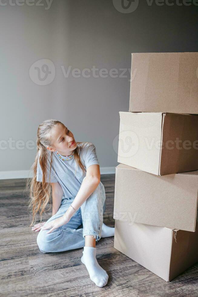 Happy adorable girl with cardboard boxes in new house at moving day photo