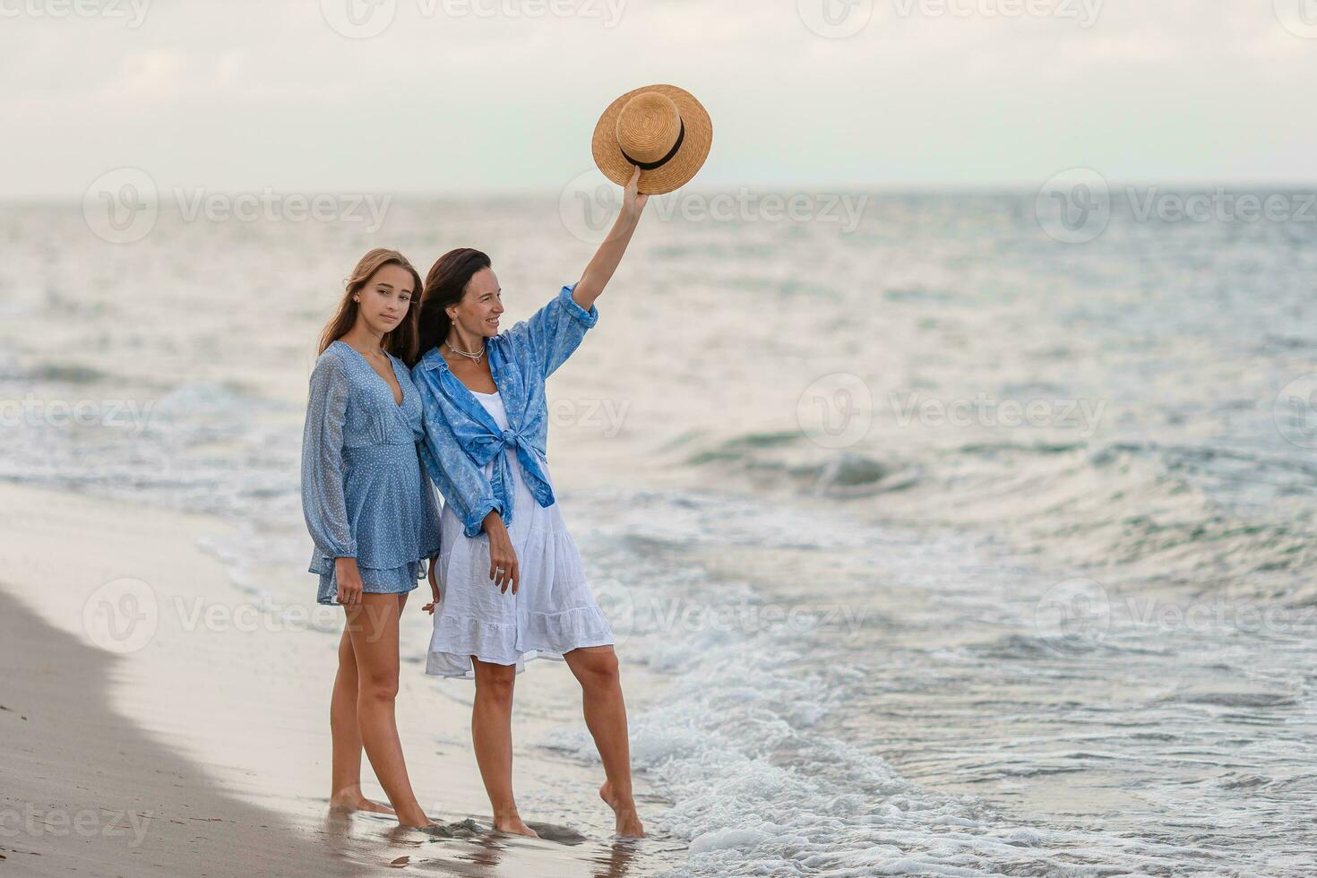 Beautiful mother and daughter at the beach enjoying summer vacation photo