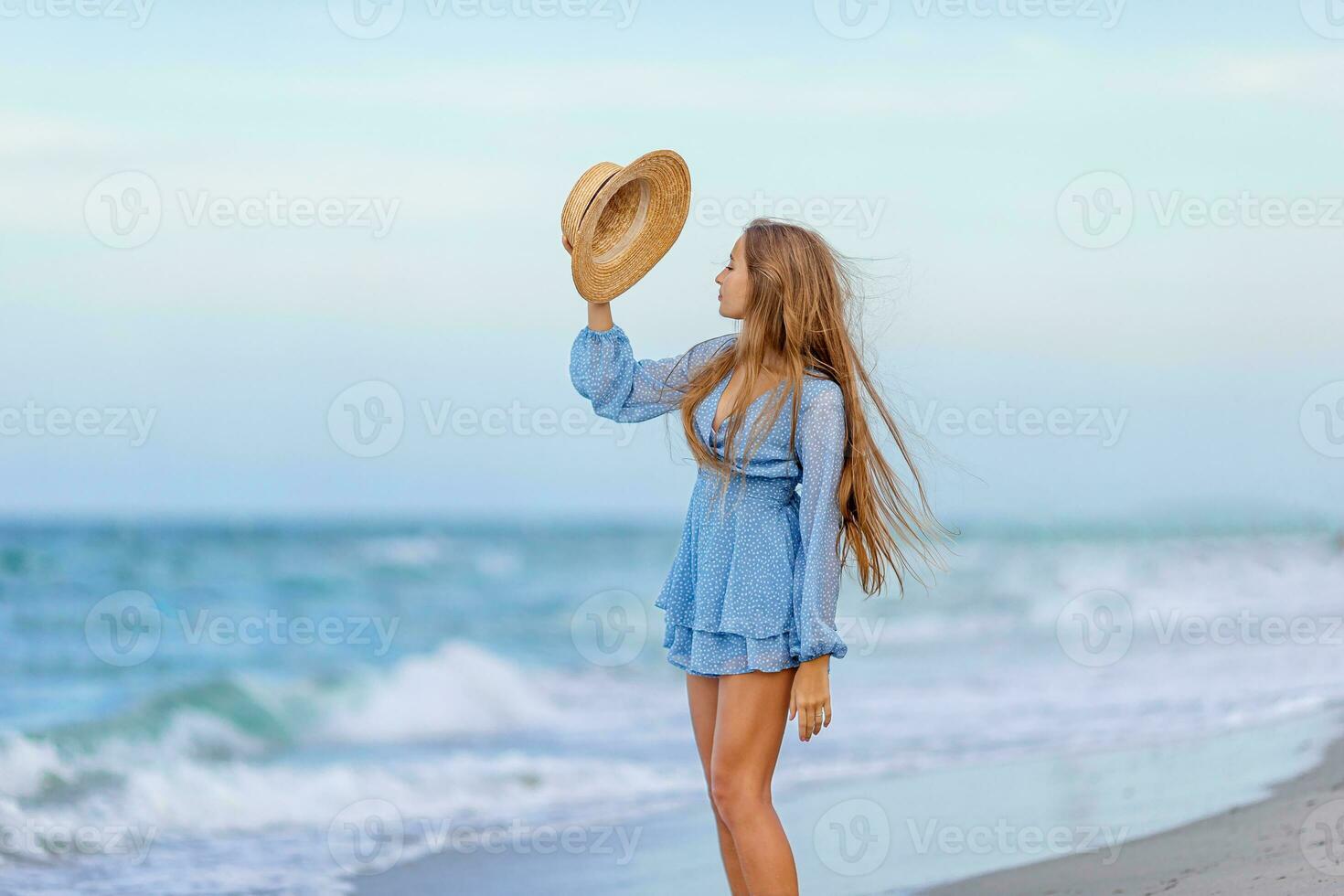 hermosa adolescente niña en tropical costa a puesta de sol. hermosa pequeño niña en vestir a playa teniendo divertida. contento niña disfrutar verano vacaciones antecedentes el azul cielo y turquesa agua en el mar foto