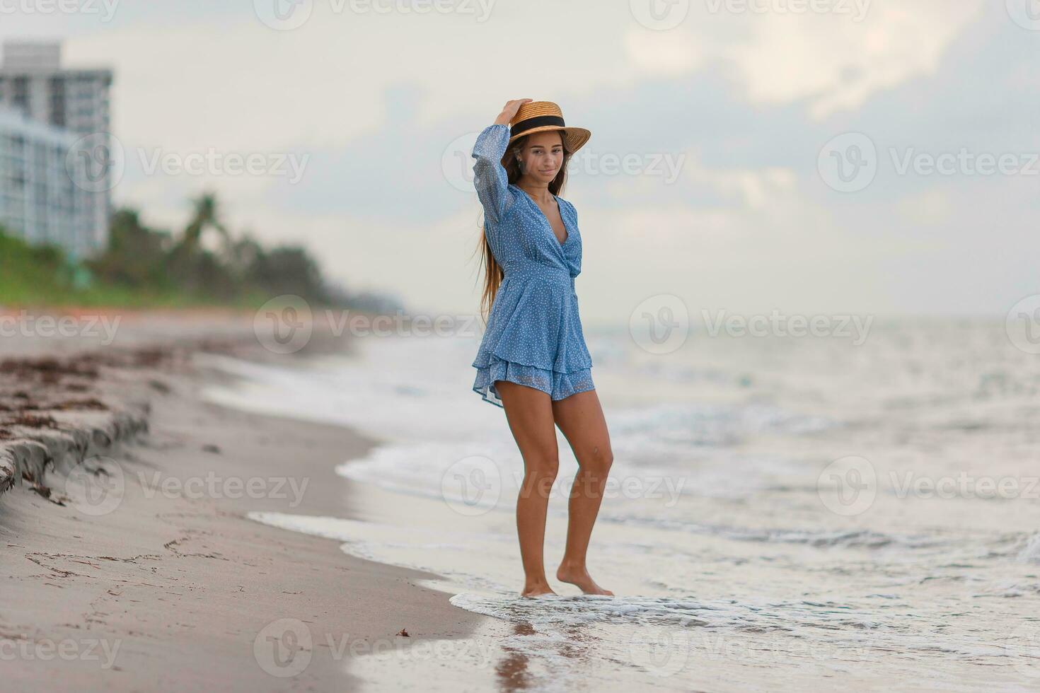 Beautiful teenager girl on tropical seashore walking at shallow water and having fun photo