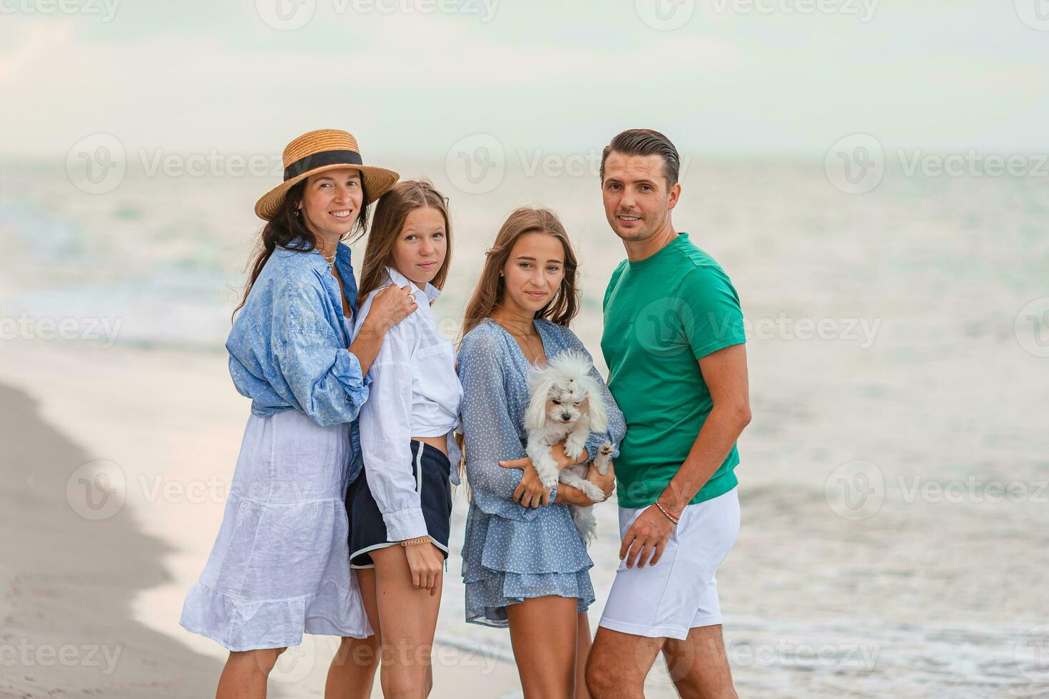 Family of four have fun together on beach vacation at sunset photo