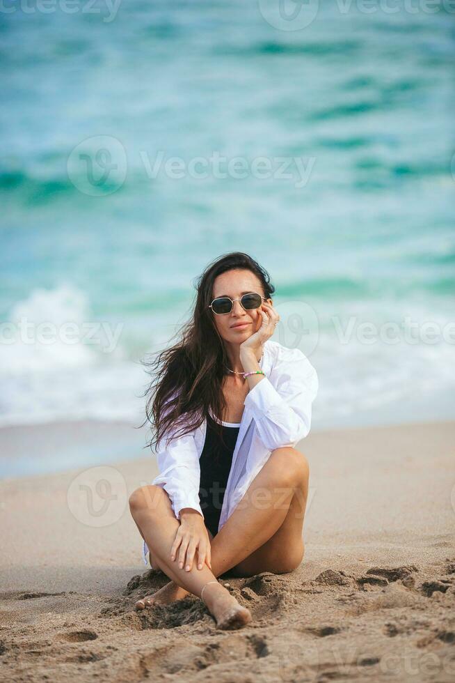 joven feliz en la playa disfruta de sus vacaciones de verano. la chica está feliz y tranquila en su estancia en la playa foto