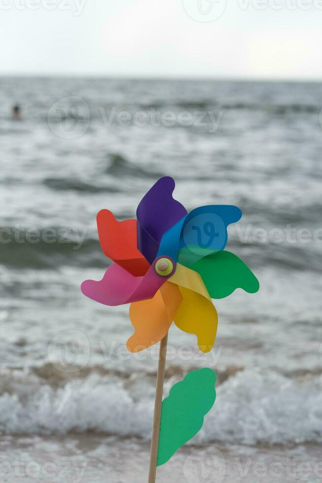 Pinwheel round colored with blowing wind against the backdrop of strong waves. photo