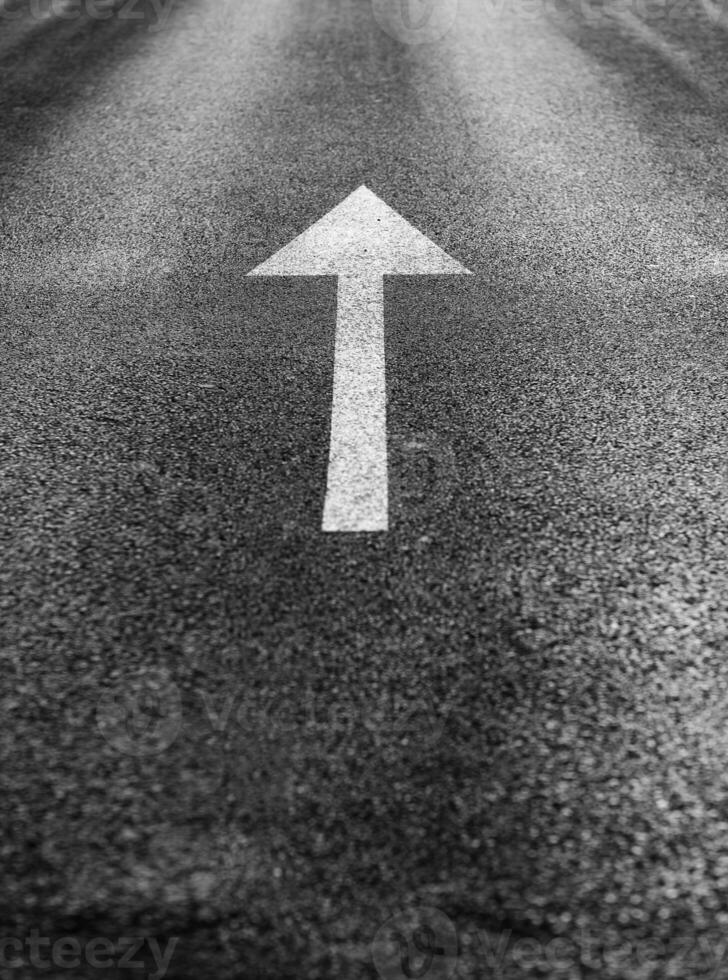 White arrow straight ahead direction of movement on dark asphalt, direction arrow sign for parking. Road markings for safe driving. Transport concept. Direction indicator. Selective focus photo