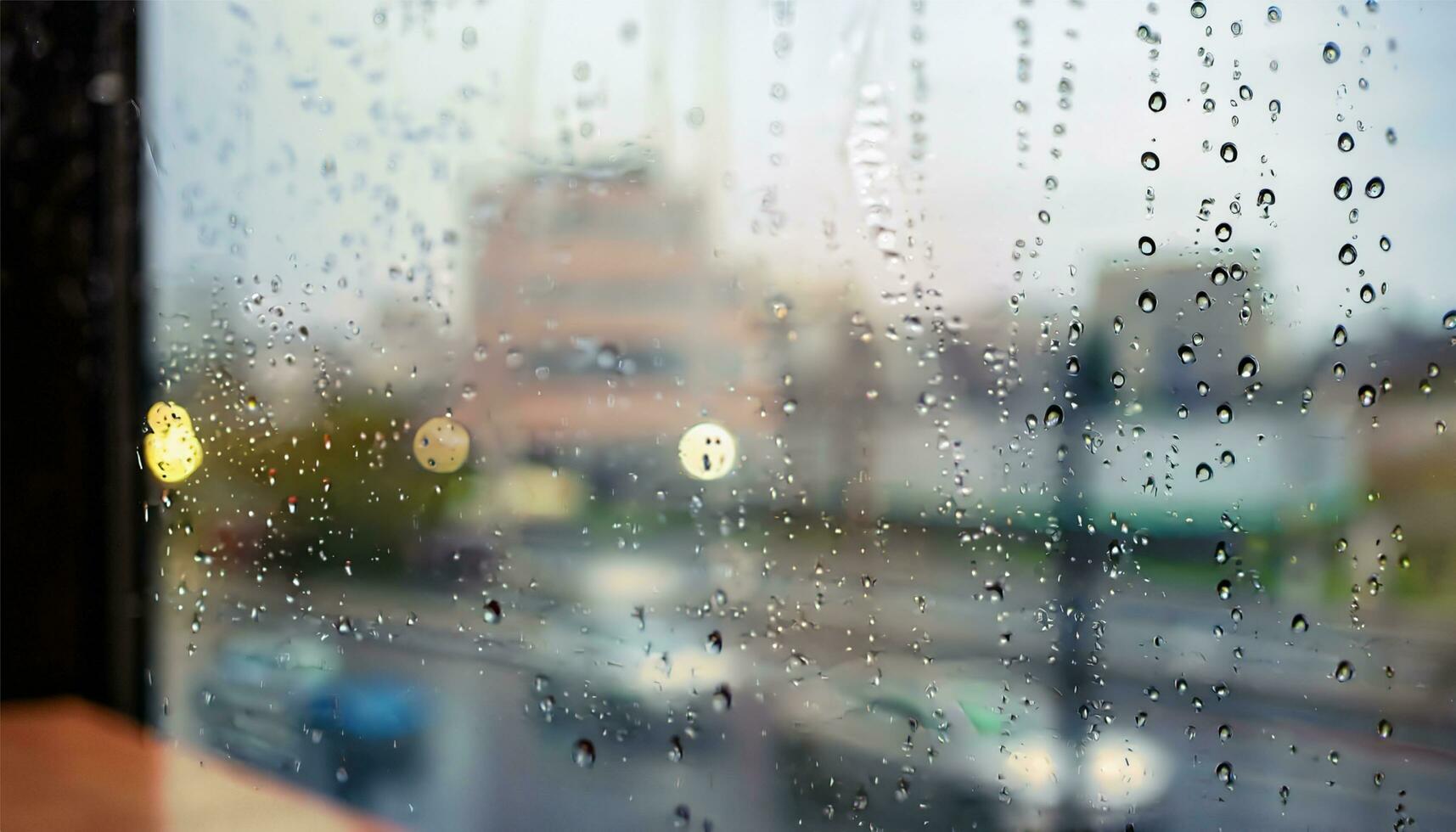 Rain drop on window glass of coffee shop and blurry city life background photo