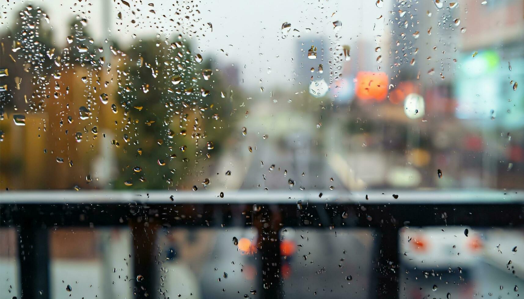 Rain drop on window glass of coffee shop and blurry city life background photo