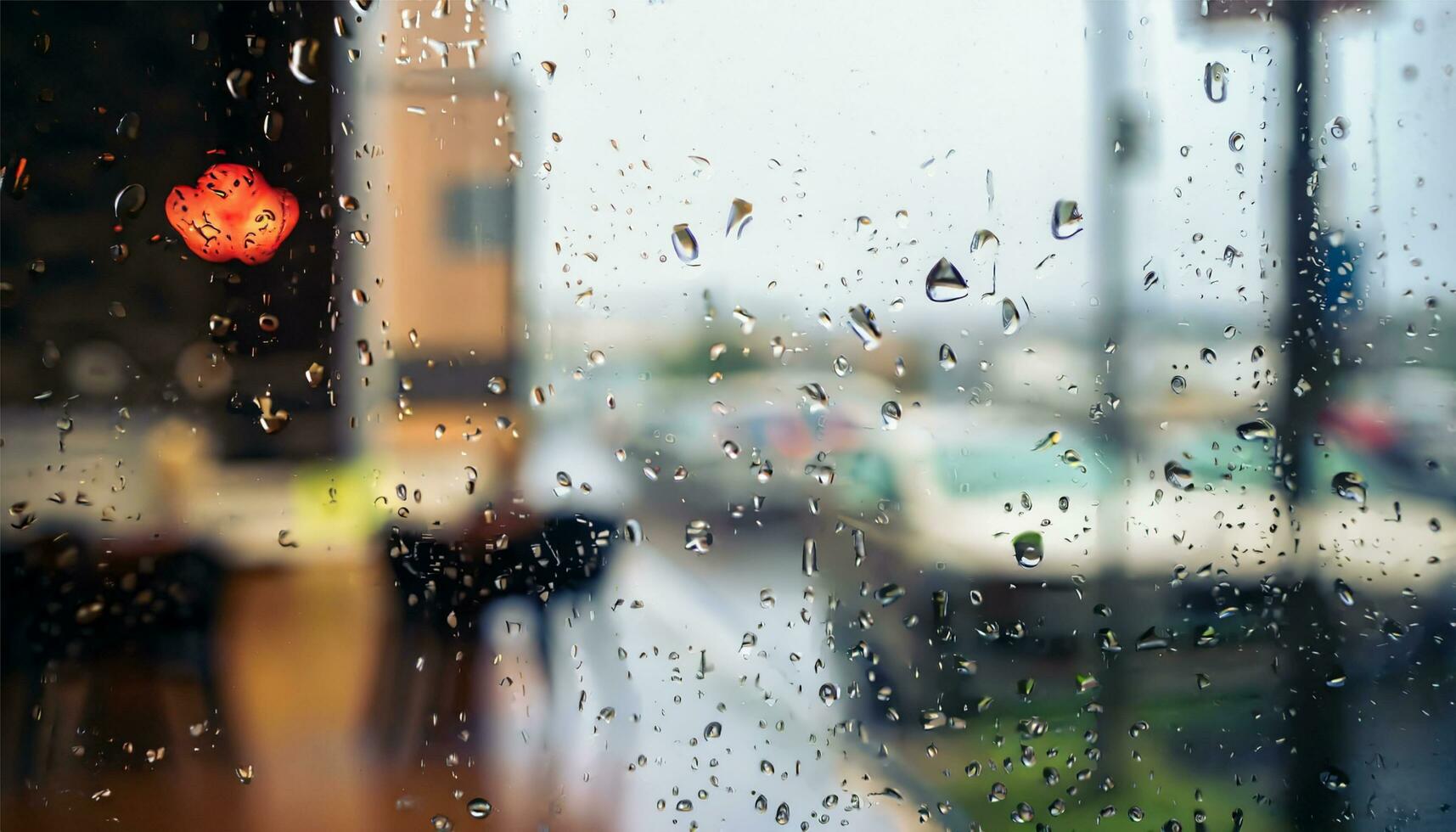 Rain drop on window glass of coffee shop and blurry city life background photo