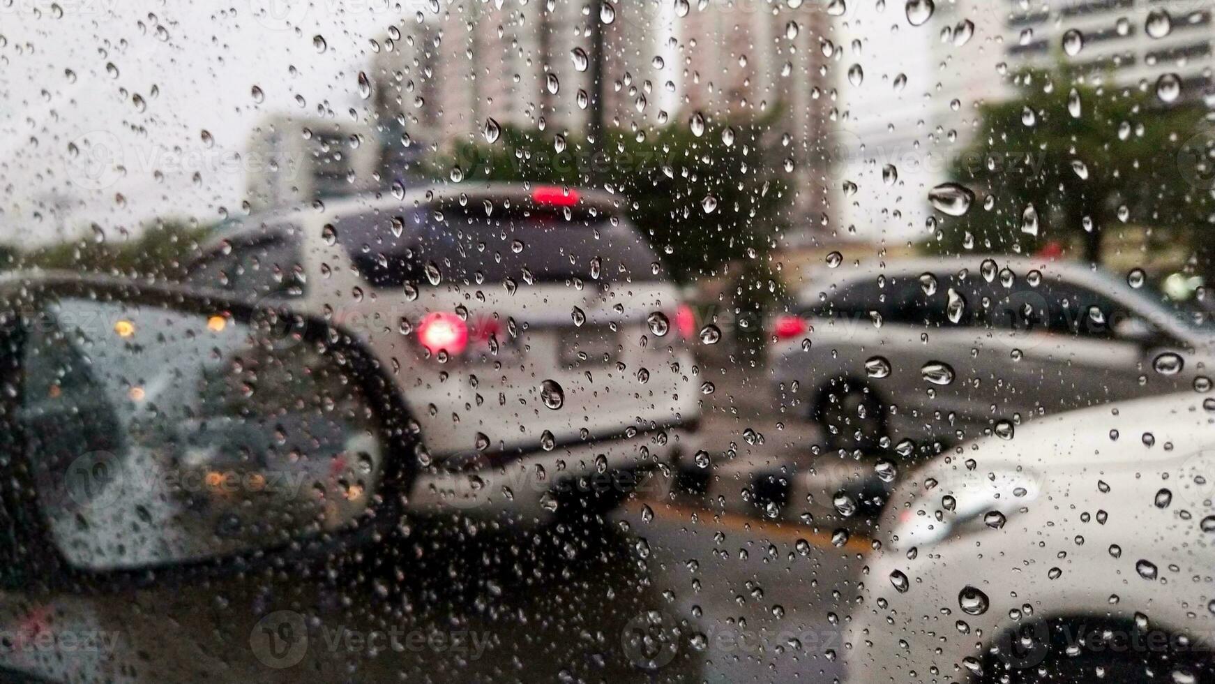 A car's window is covered in raindrops as it travels down a busy route photo