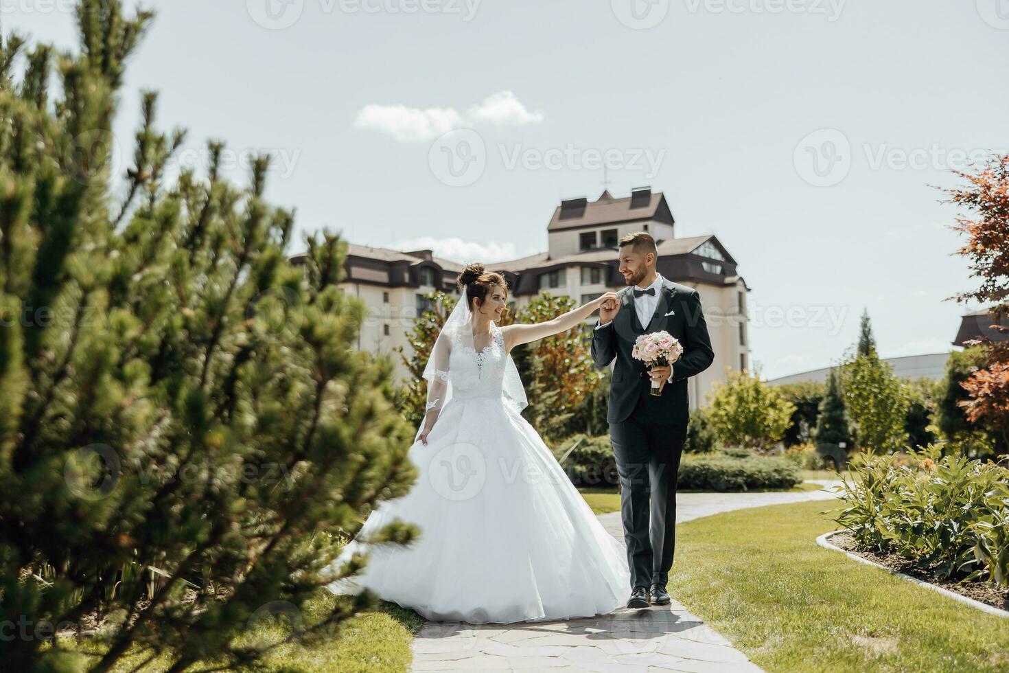 Happy husband and wife. Wedding day. Beautiful nature. Walk during the photo session. They smile at each other. Holding hands.