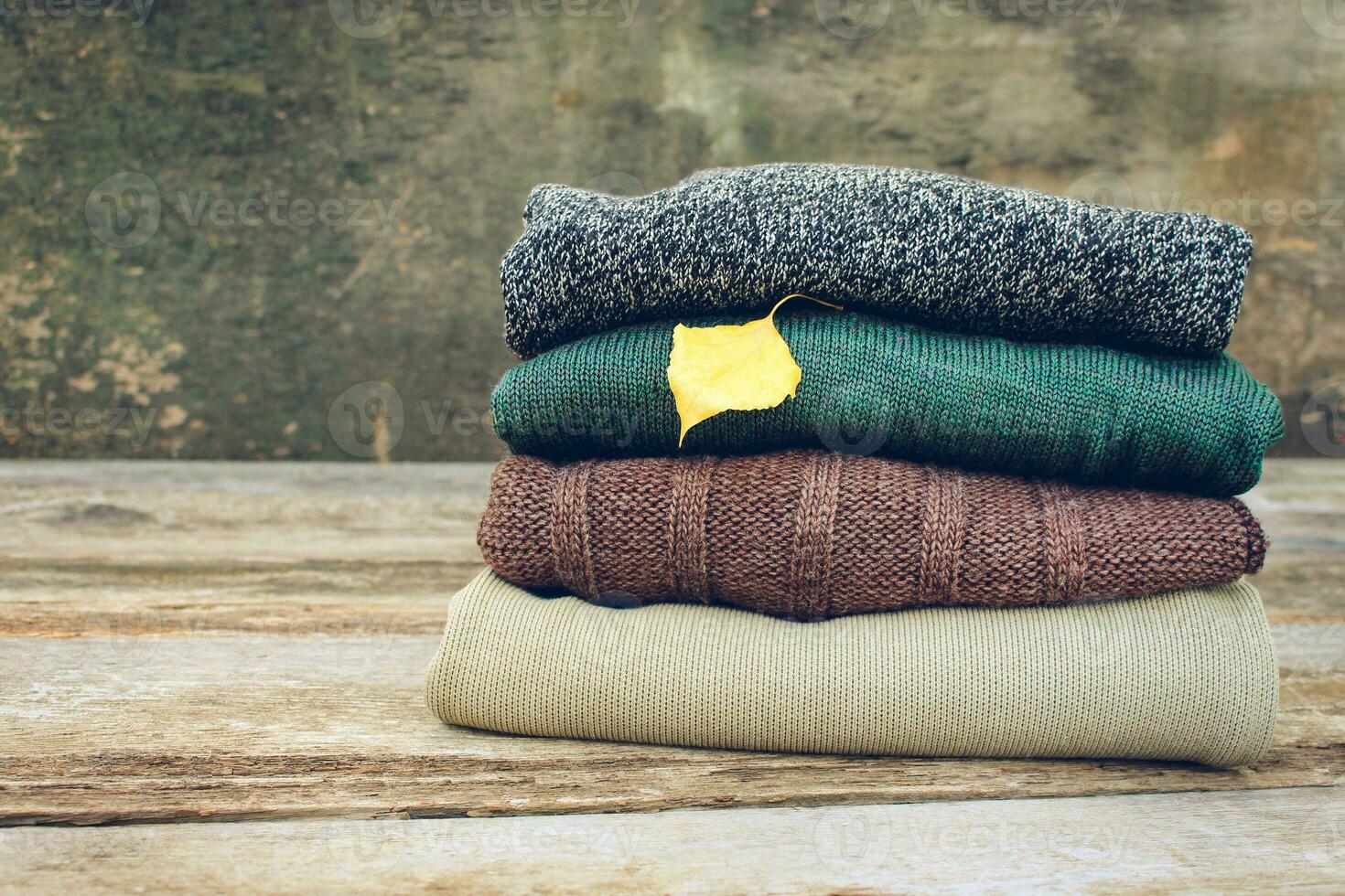 Pile of colorful warm clothes on wooden background. Toned image. photo