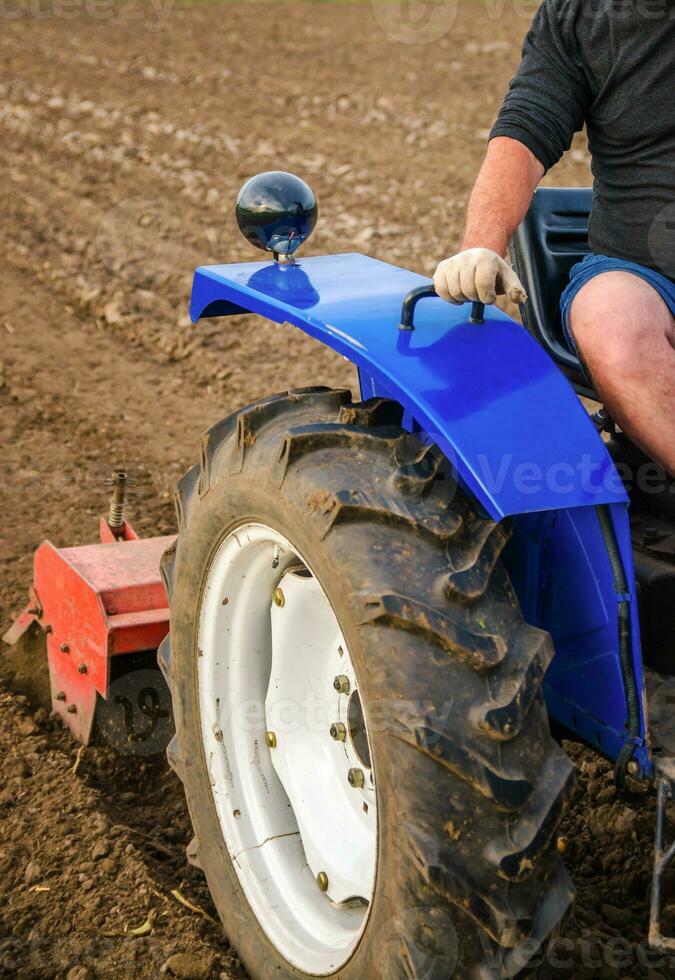 el tractor es cultivando el suelo en el granja campo. aflojando y mezclando reblandecimiento de el suelo y destrucción de el raíz sistema de el anterior cosecha. tierra cultivo. agricultura. foto