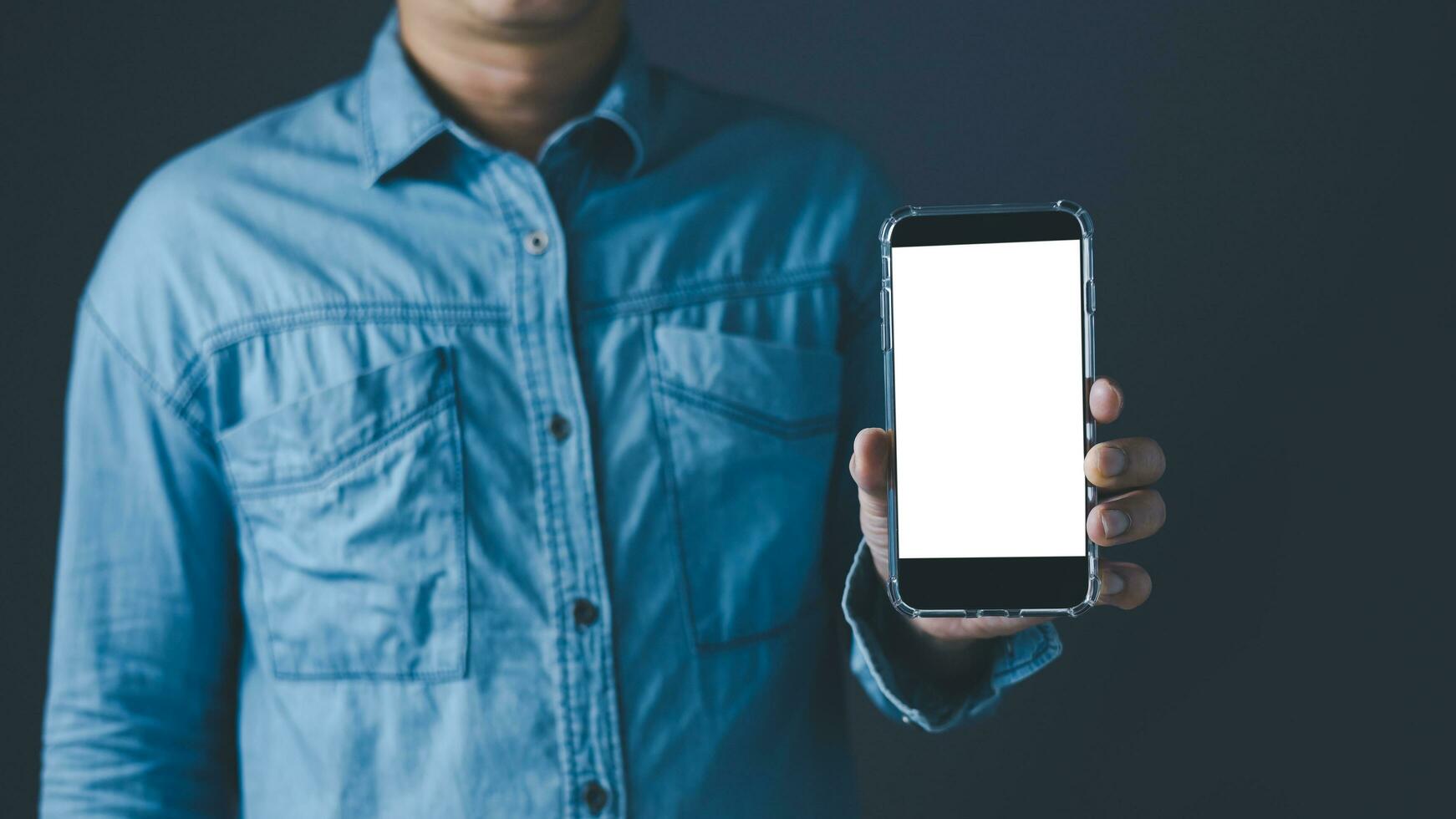 el izquierda mano hombre demostración un negro inteligente teléfono o Teléfono móvil y un blanco pantalla monitor para Bosquejo contenido a azul tono antecedentes. foto