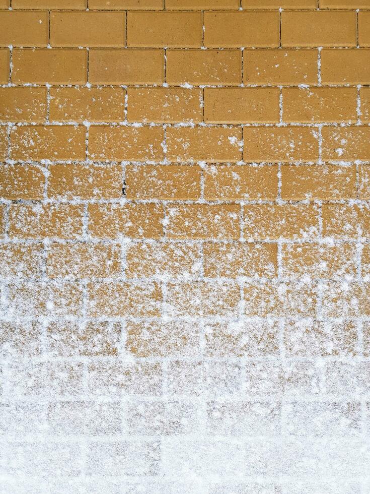Yellow sidewalk partially covered with snow at the bottom. Pavement vertical background. Place for your text here photo