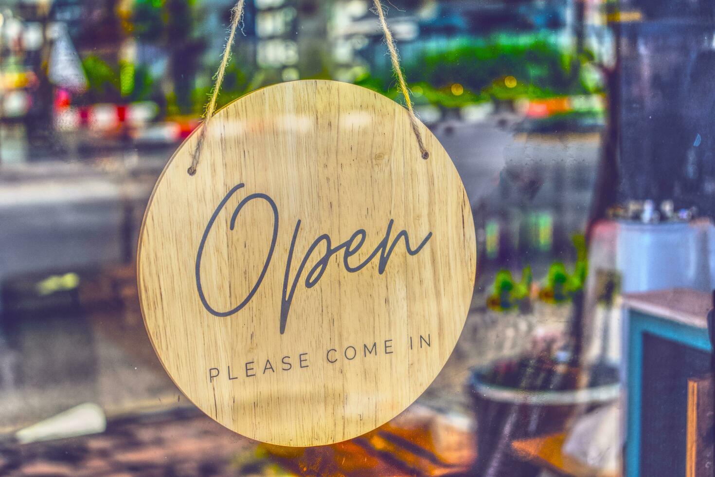 circular sign hung on the glass door of the coffee shop saying Open please come in photo