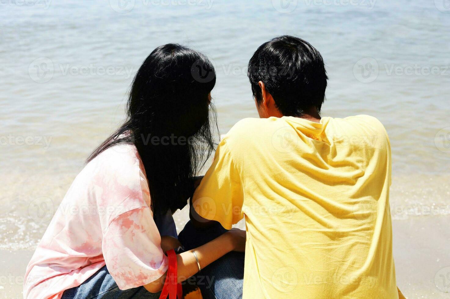 Rear view of sweet couple sitting on the beach photo