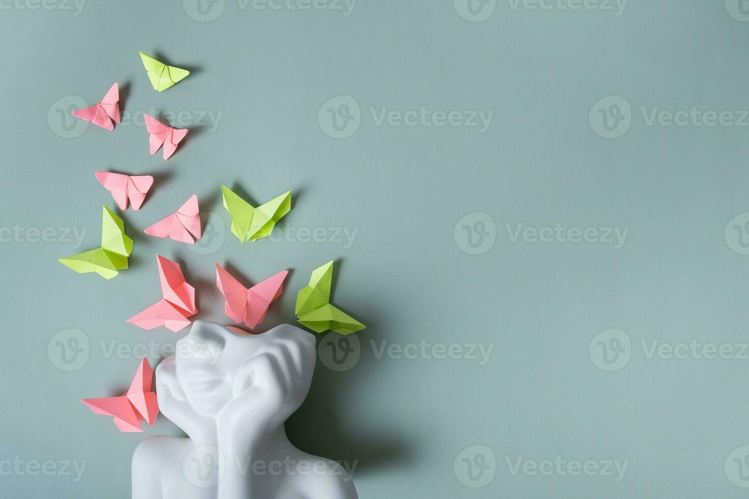 A figurine of a head with butterflies on a colored background. Mental health concept. Copy space photo