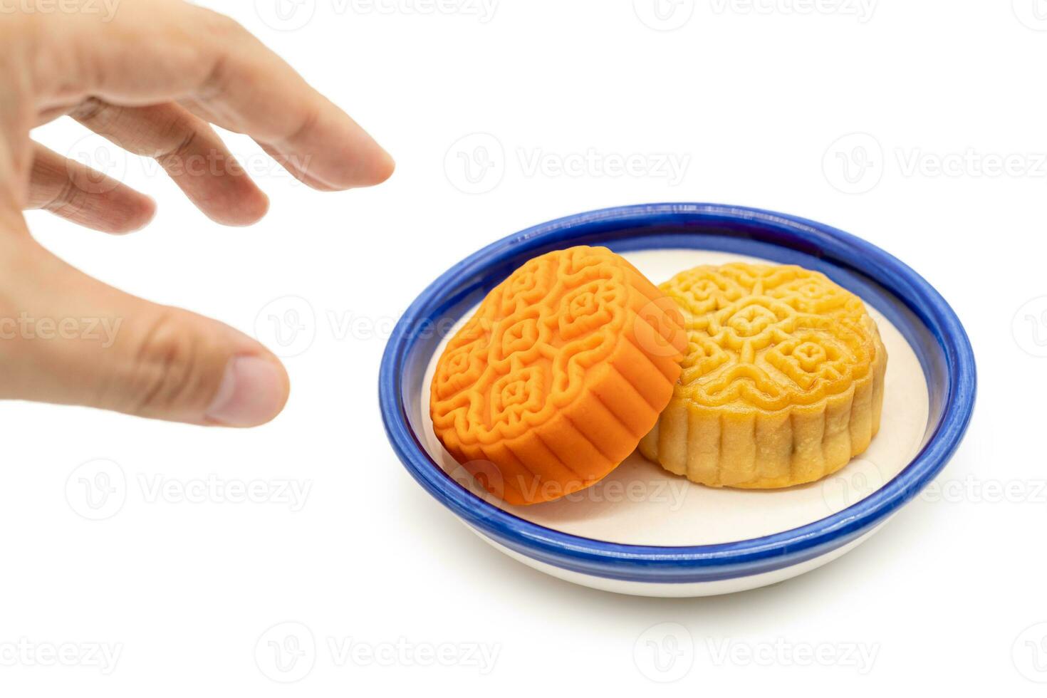 A hand taking moon cake on plate isolated on white background. Concept for Mid-Autumn Festival. photo