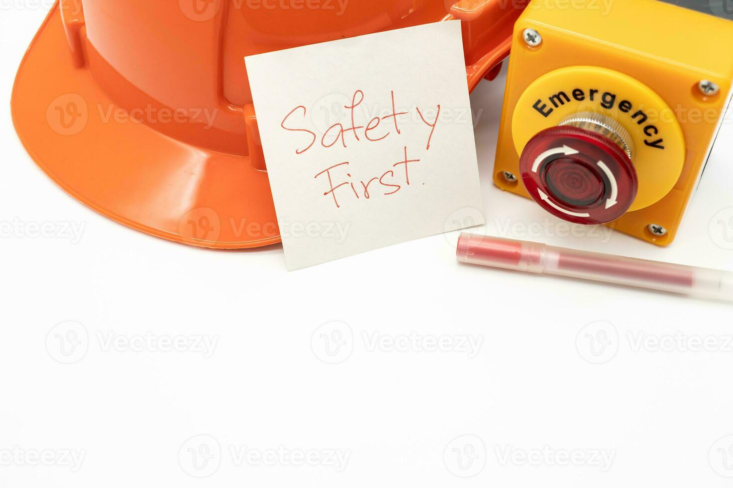 Orange safety hat with message Safety First, Red Pen and Emergency Stop Button isolated on white background. Safety First Concept. Copy Space for text. photo