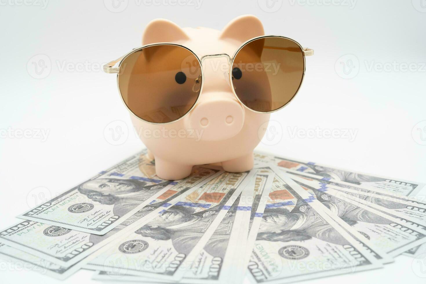 Piggy bank preparing for vacation with Sunglasses on Dollars. Saving money, travel concept. Isolated on  background. photo