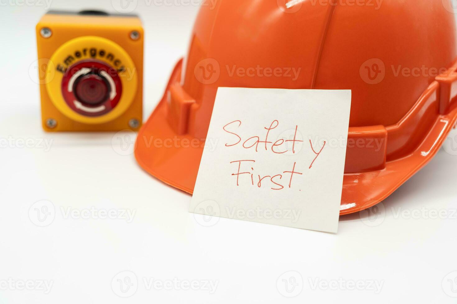 Orange safety hat with message Safety First and Emergency Stop Button isolated on white background. Safety First Concept. photo