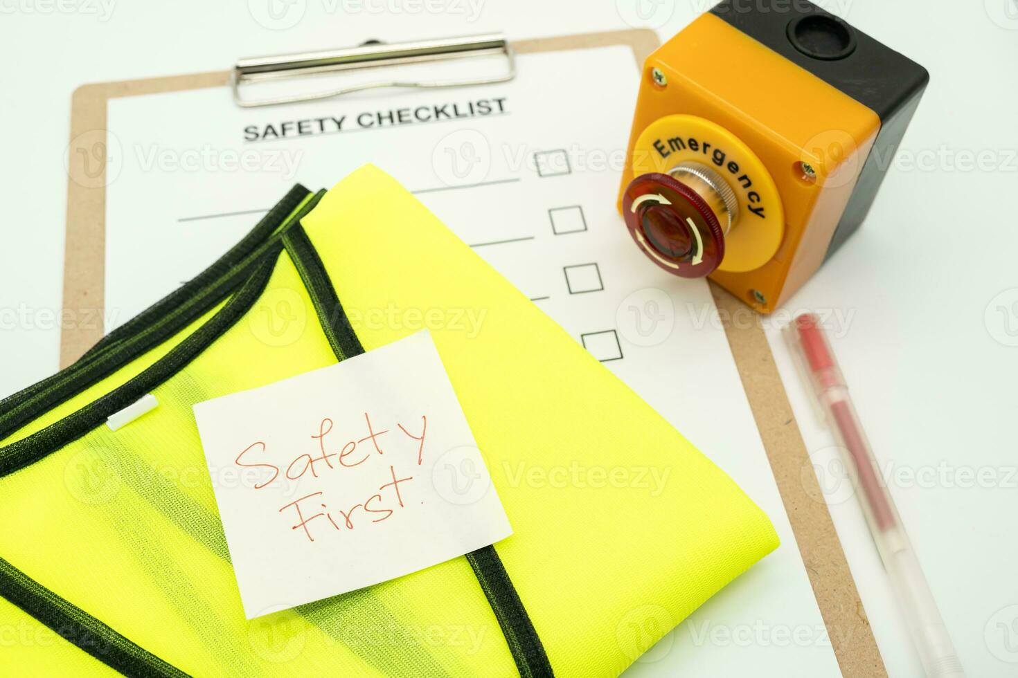 Safety First message on paper. Reflective vest, safety hat or helmet and Emergency Stop Button. Safety First Concept. Blank checklist paper during safety audit and risk verification. photo