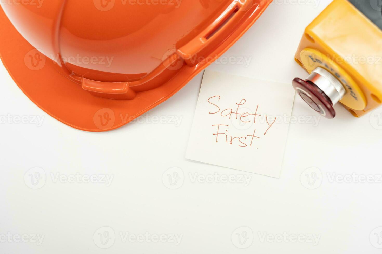 Orange safety hat with message Safety First and Emergency Stop Button isolated on white background. Safety First Concept. photo