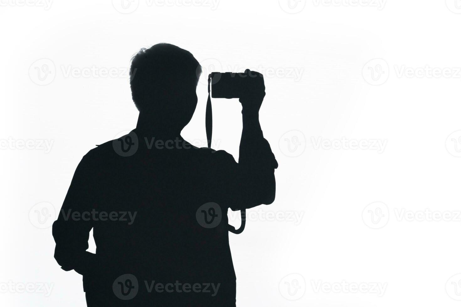 Silhouette man pose using camera. Silhouette man takes photo with camera isolated on white background.