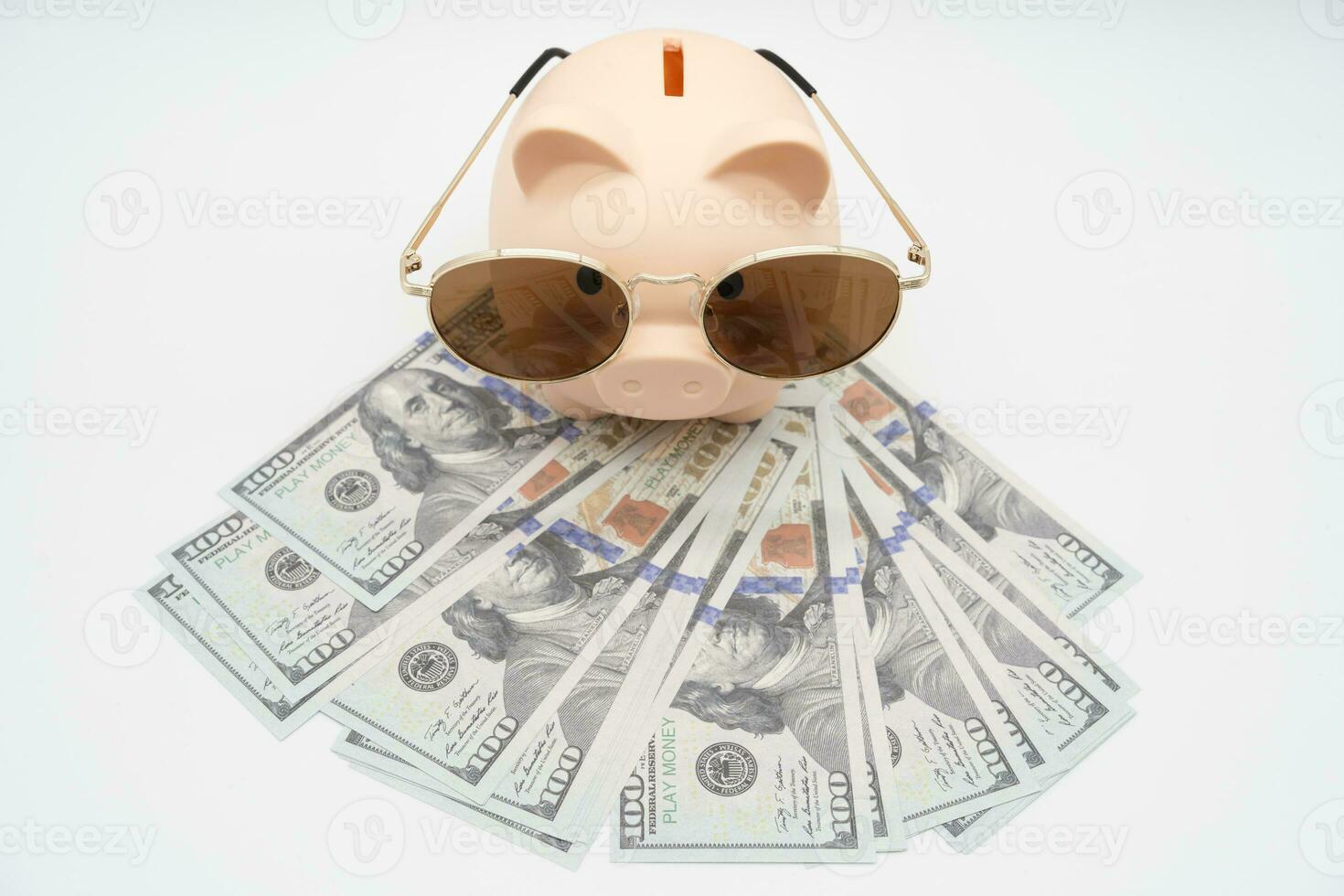 Piggy bank preparing for vacation with Sunglasses on Dollars. Saving money, travel concept. Isolated on  background. photo