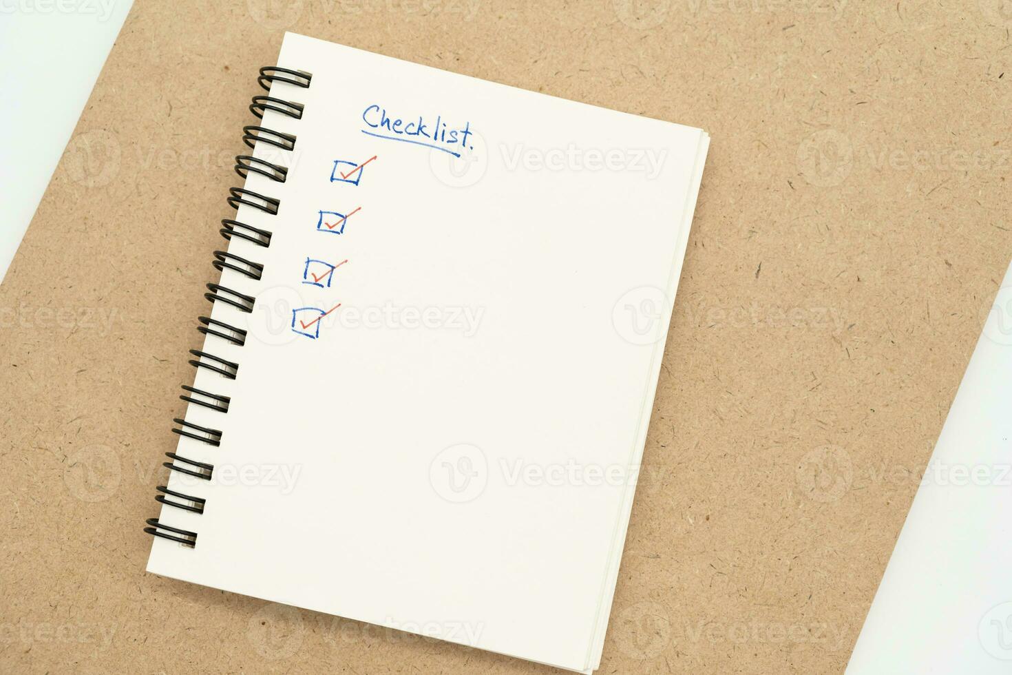 Top view of notebook with handwritten Checklist text. Checklist concept, checklist box with red checkmark. photo