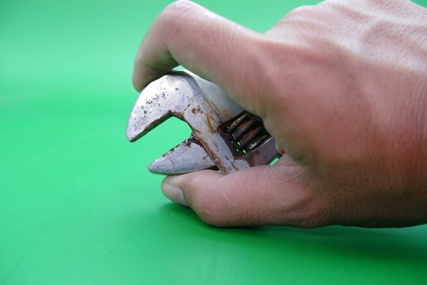 hand holding a wrench over a green background. photo
