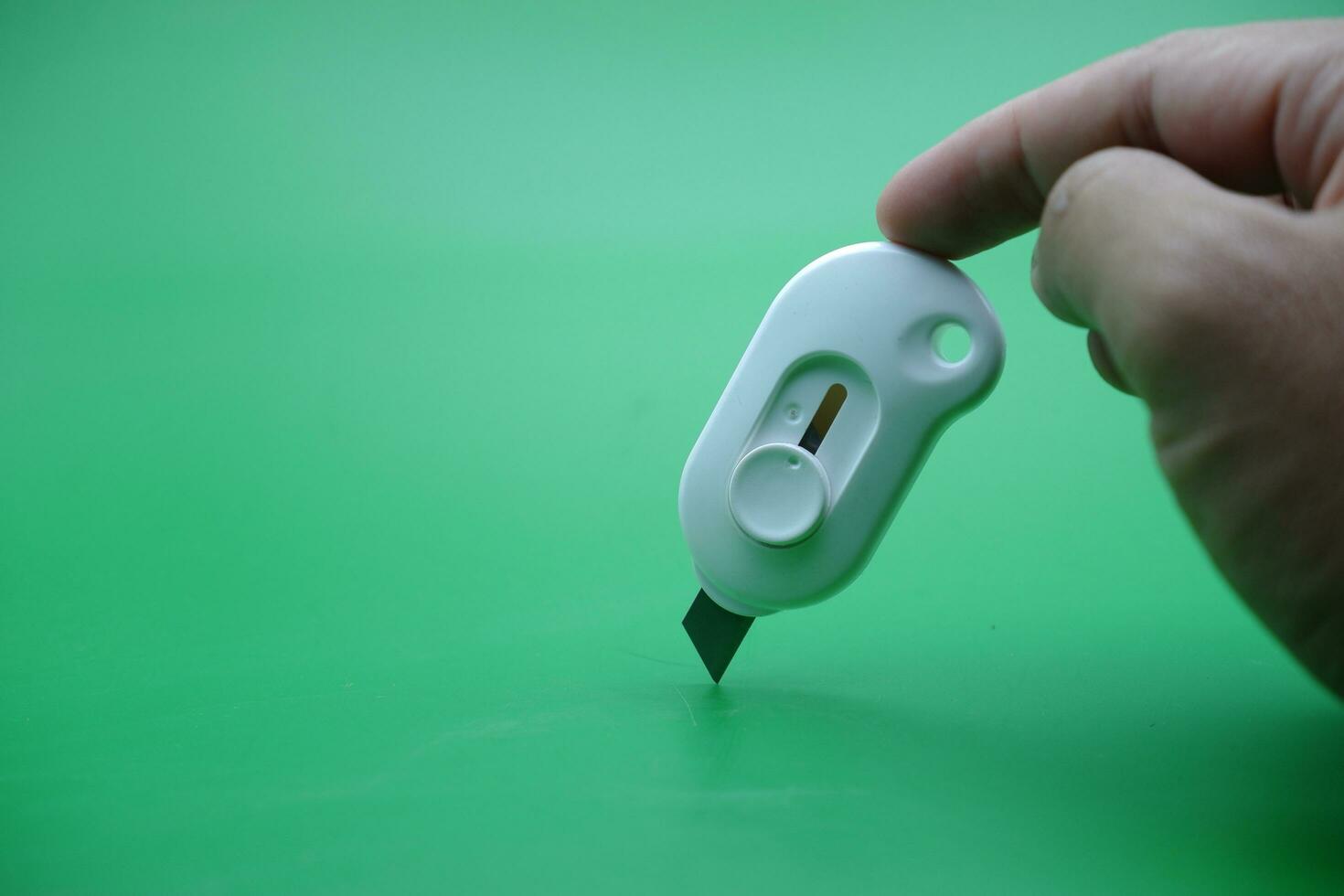 hand holding a white cutter isolated on a green background. photo