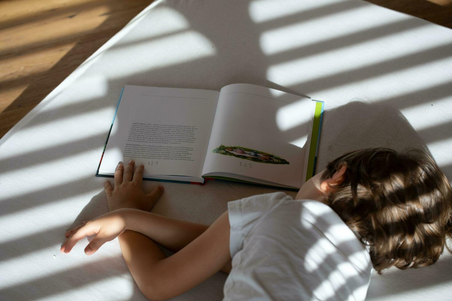 a child laying on a bed reading a book photo