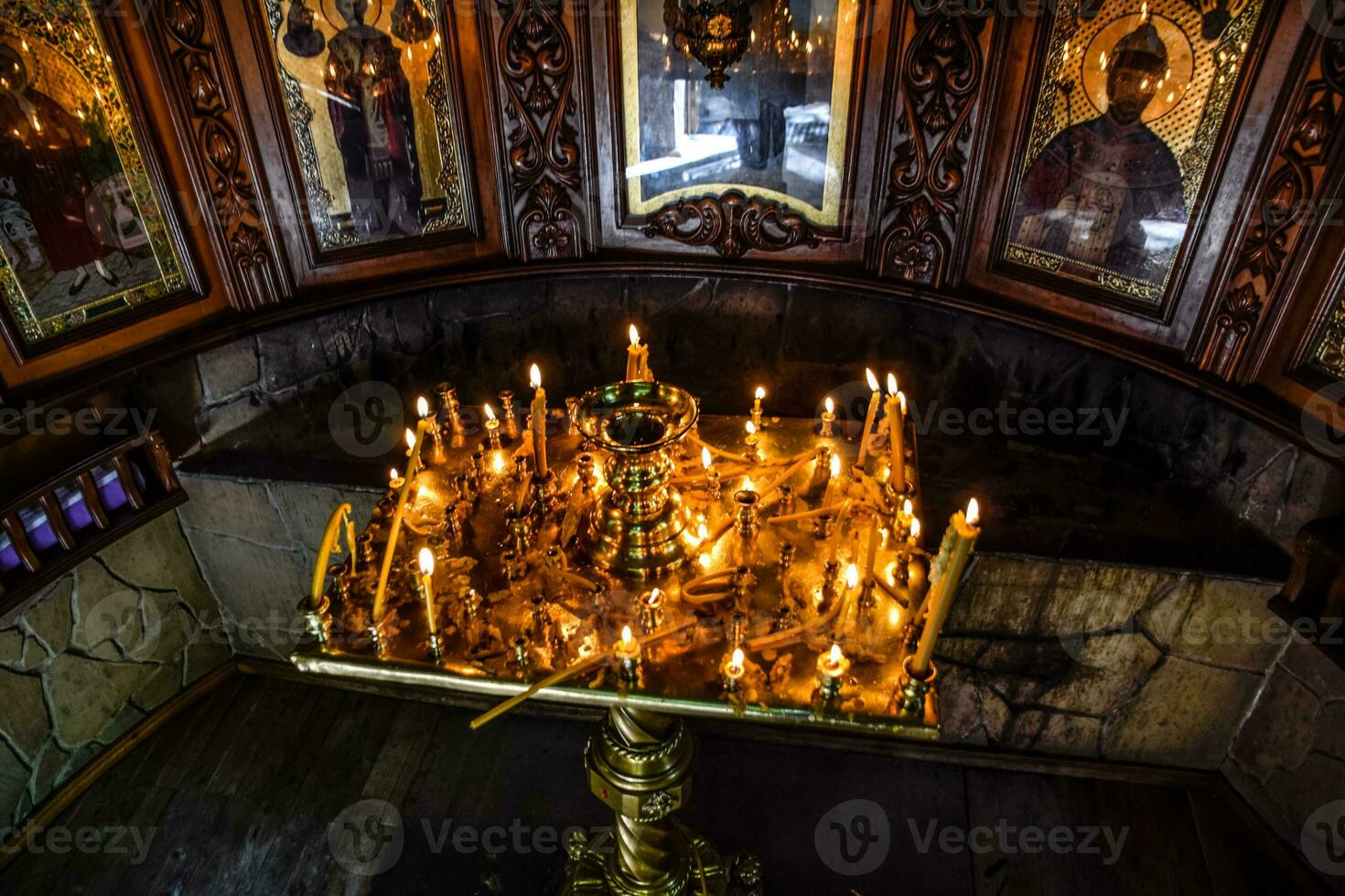 Burning candles on a stand near the icons in the chapel. photo