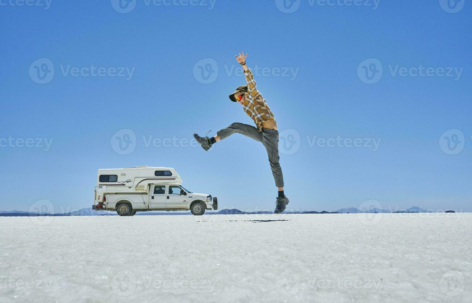 Bolivia, Salar de Uyuni, boy jumping at camper on salt lake photo