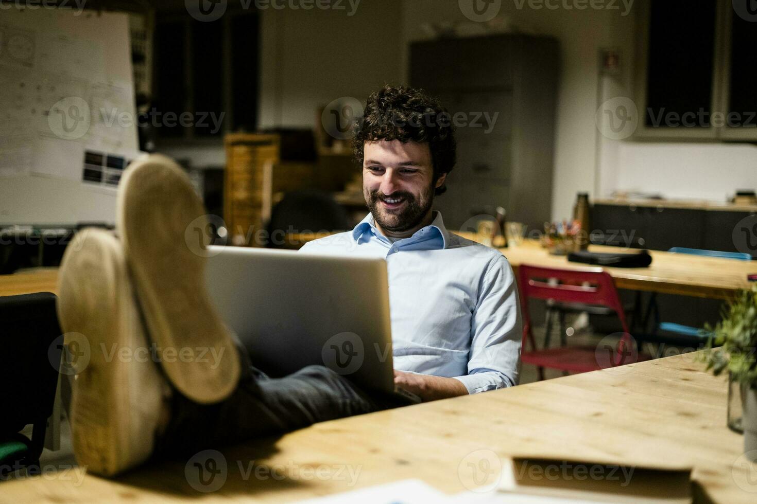 Businessman using laptop in office with feet on desk photo