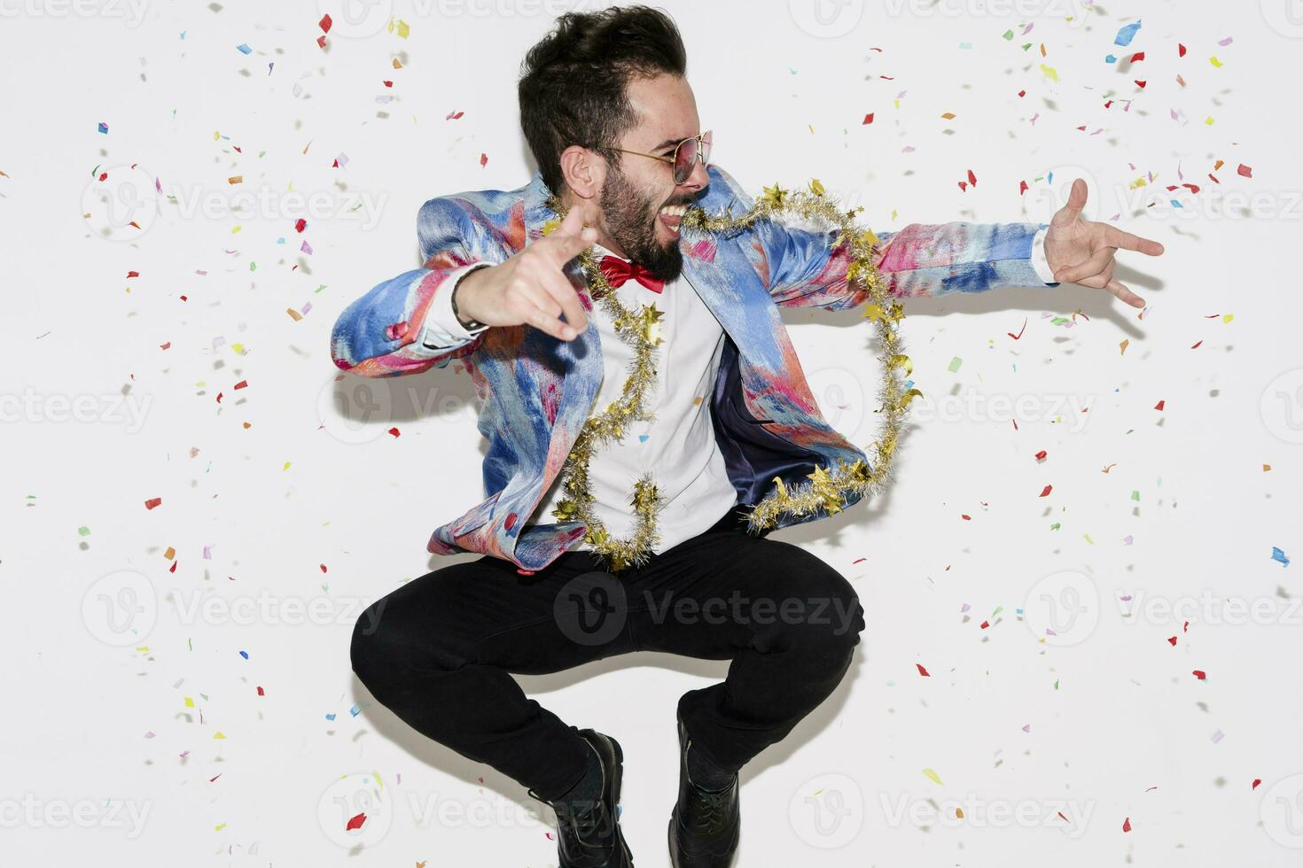 Stylish man wearing a colorful suit and sunglasses celebrating a party and jumping photo