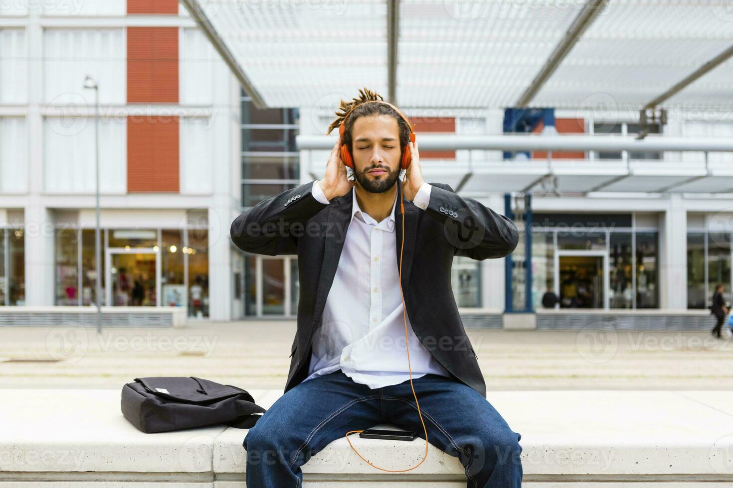 retrato de joven empresario con rastas escuchando música con auriculares y célula teléfono foto