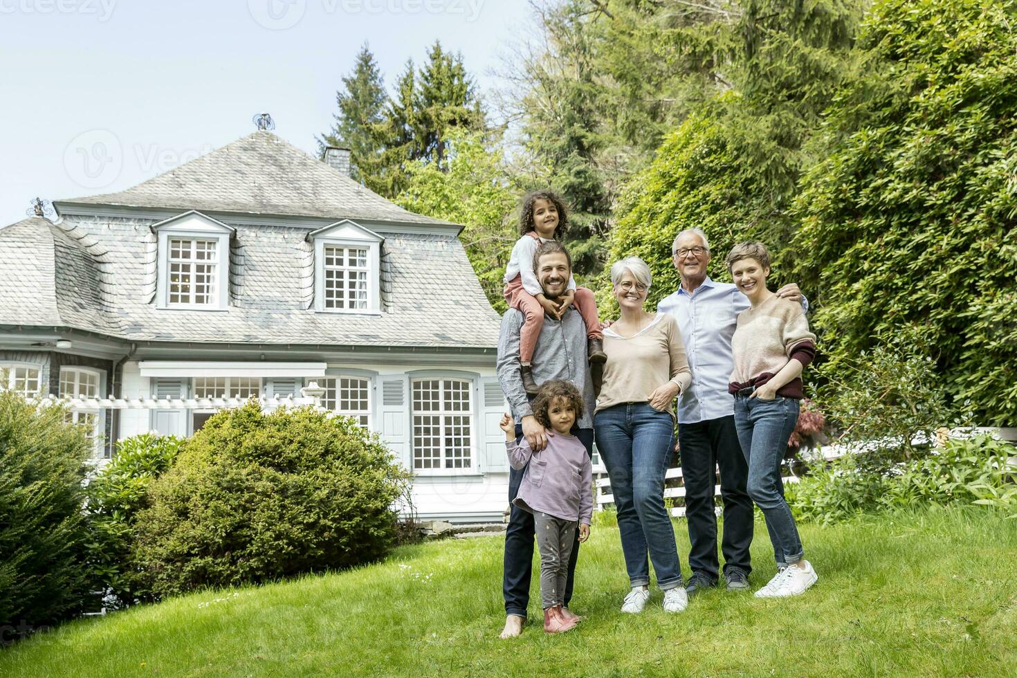 contento extendido familia en pie en jardín de su hogar foto