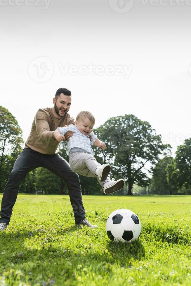 Happy father playing football with son in a park photo