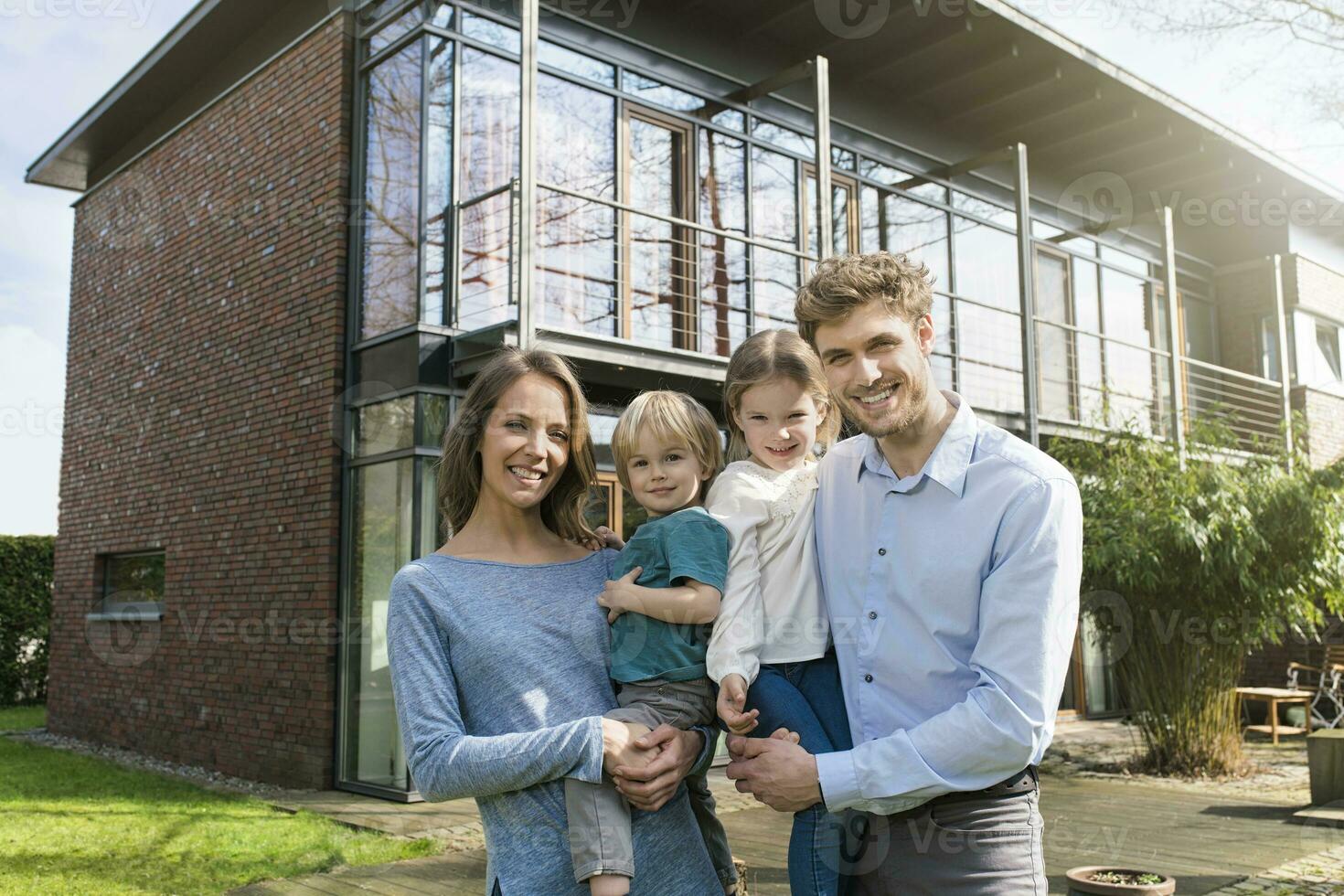 retrato de sonriente familia en frente de su hogar foto