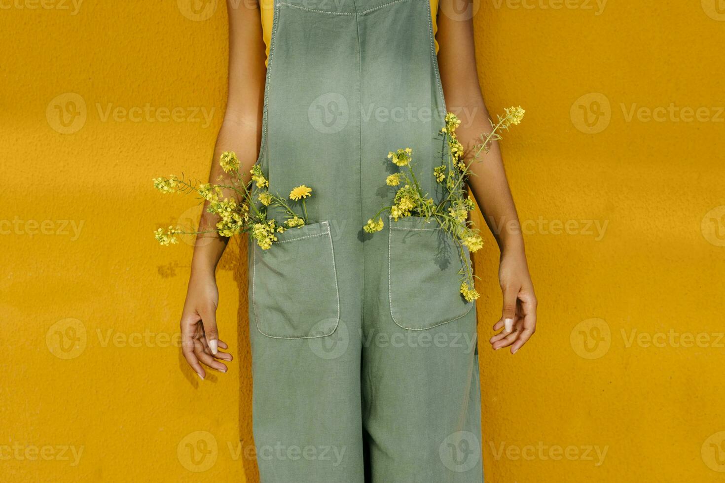 Midsection of woman wearing overalls with yellow flowers in pockets photo