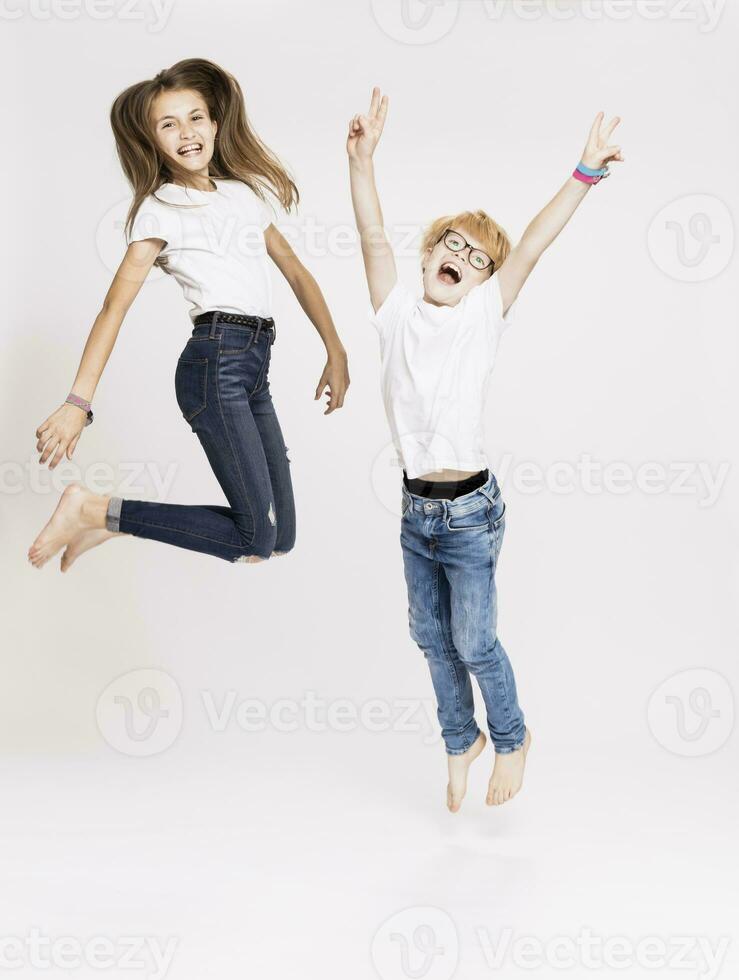 Cheerful siblings jumping against white background photo