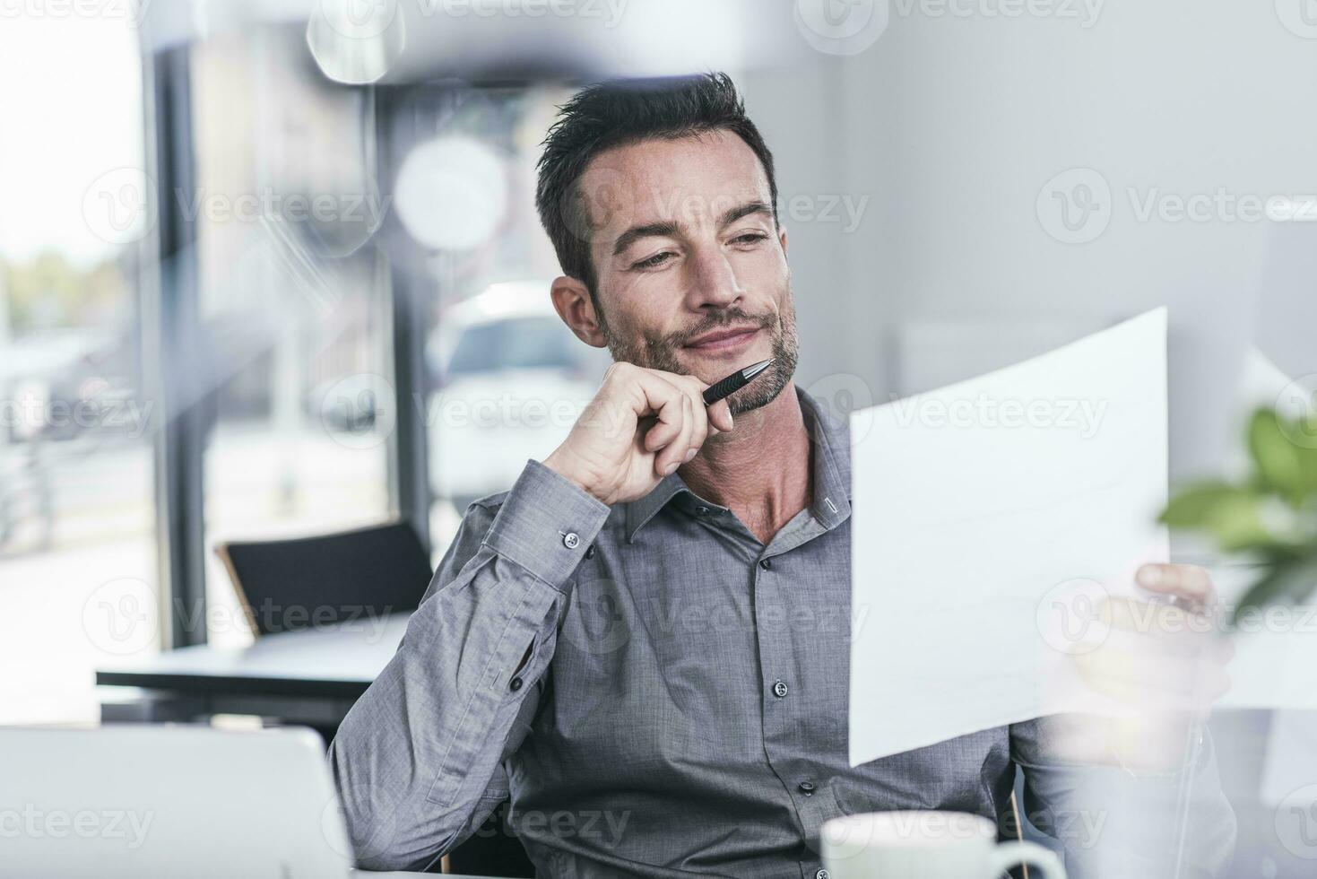 Businessman sitting in office, reading a letter photo
