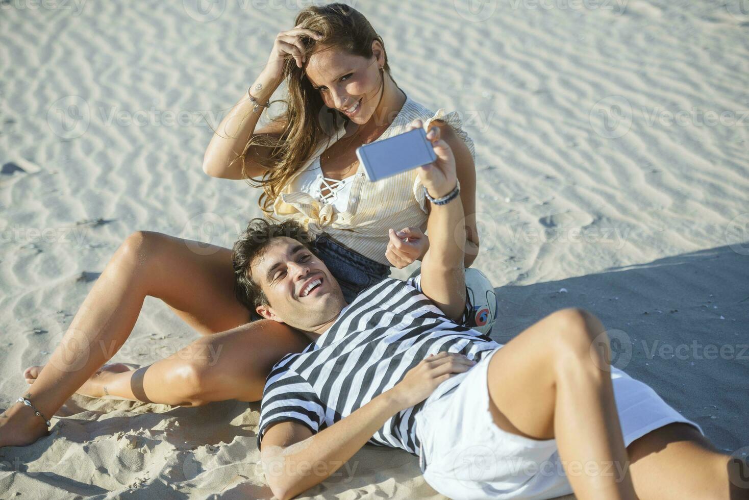 Happy affectionate young couple taking a selfie on the beach photo